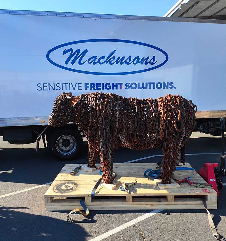 Macknsons freight truck behind a metal cow