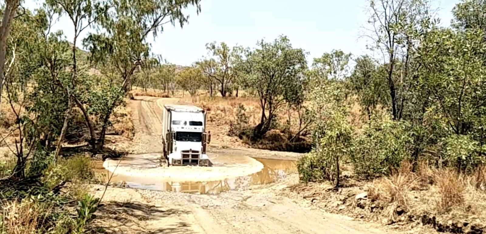 A truck driving through a large puddle