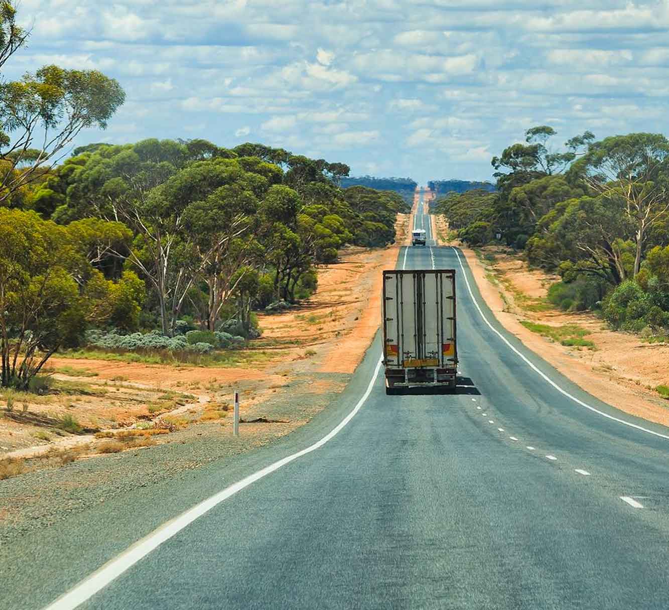 Trucks driving along a long stretch of road